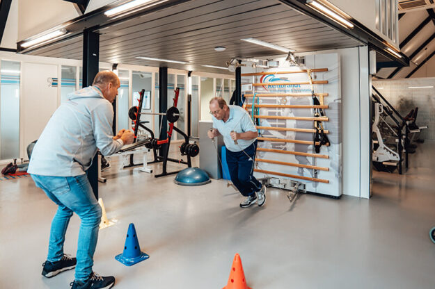 Rembrandt Fysiotherapie & revalidatie – sportfysiotherapie (1) Man doet oefeningen bij therapeut Hans Bloo tijdens sportfysiotherapie in de oefenzaal met een rek Rembrandt Fysiotherapie & Revalidatie Veenendaal Amerongen Duiven Rhenen Lienden