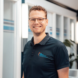 Profielfoto van Bob Verweij die als fysiotherapeut poseert voor de camera in een grijze hoodie en blauwe polo