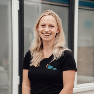 Profielfoto leoniek van woudenberg Profielfoto van Leoniek van Woudenberg die lachend naar de camera kijkt in een zwart shirt met logo.