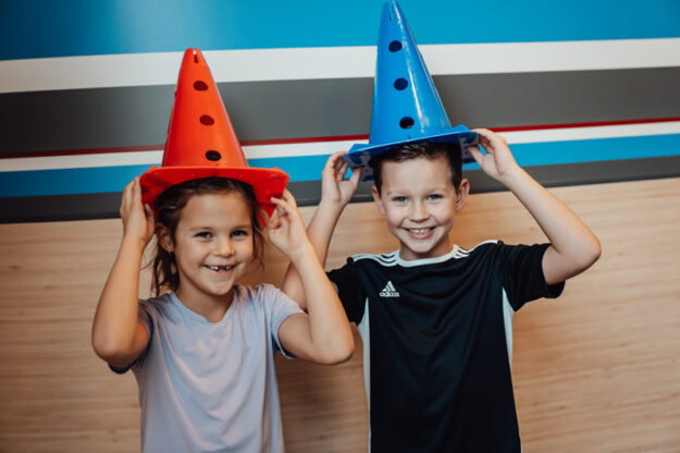 Twee kleine patiënten van kinderfysiotherapie hebben pionnen op hun hoofd.