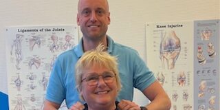 Een fysiotherpeut samen met een patiënt in een behandelkamer